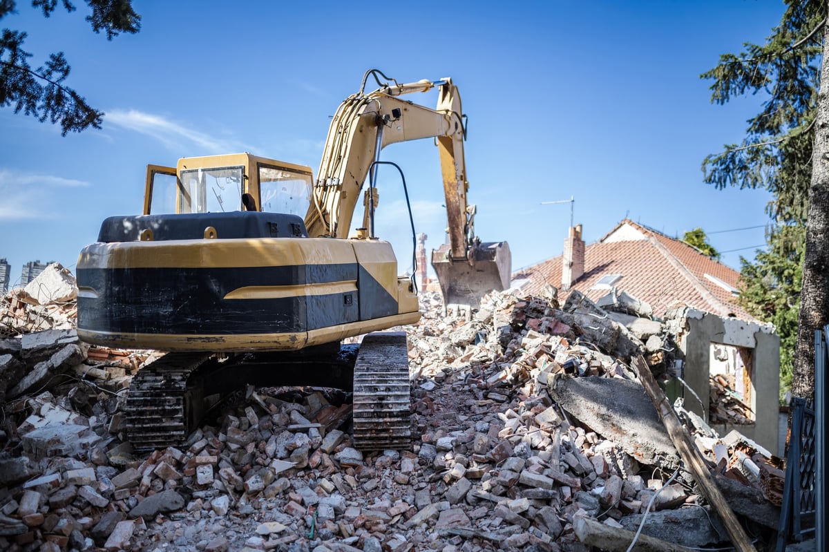 Small hydraulic excavator sorting through a pile of debris