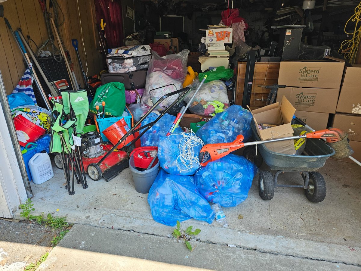 Open garage door revealing a space filled with clutter and belongings