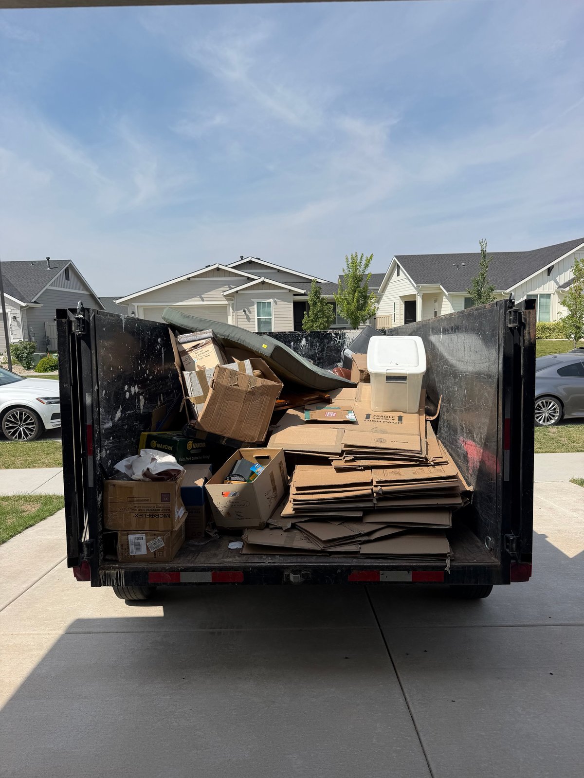 Open dumpster truck filled with boxes and debris in a residential neighborhood
