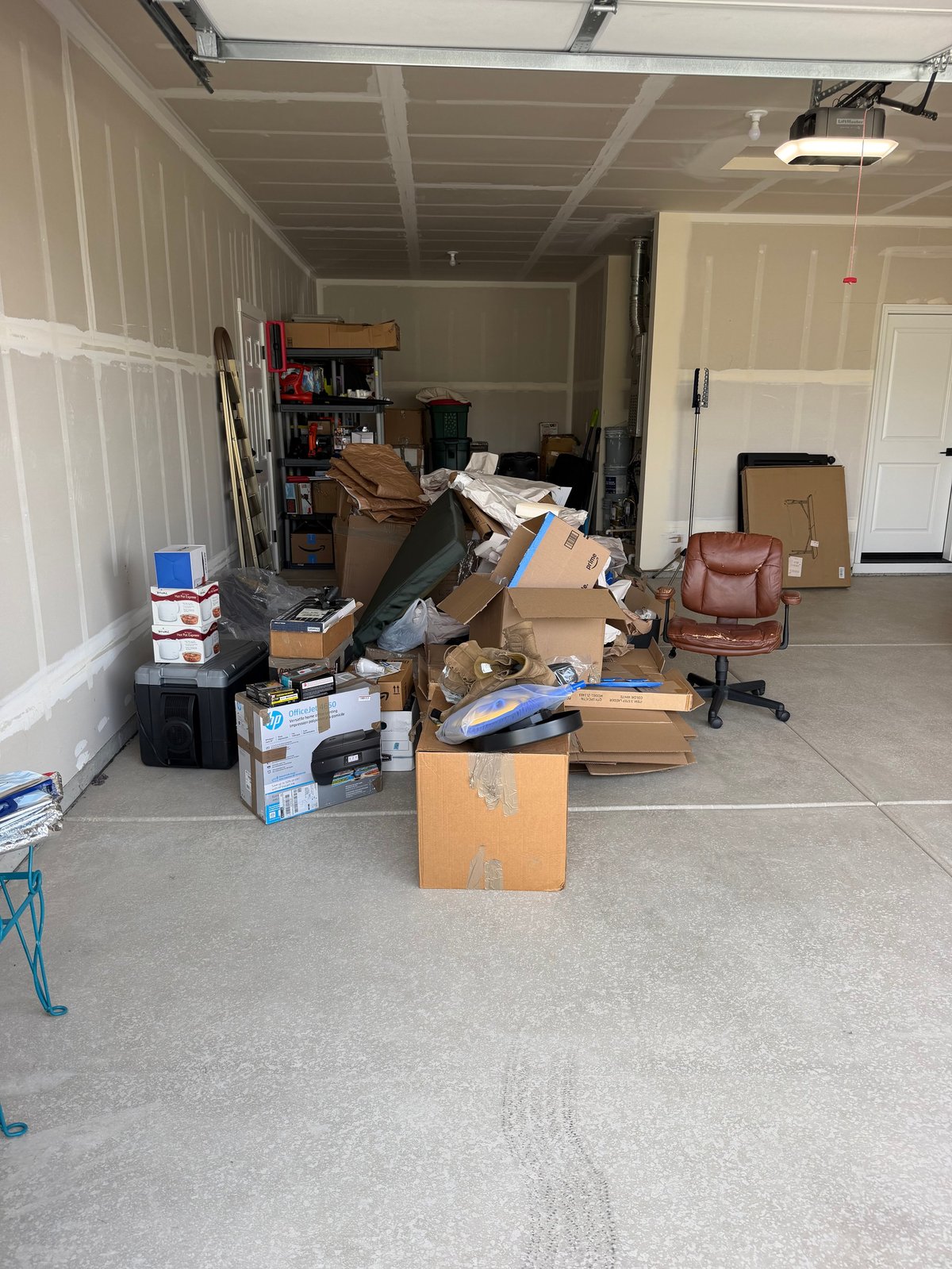 Cluttered garage interior with boxes, bins and furniture scattered on the floor